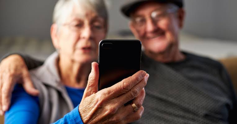 Elderly couple looking at a smartphone together.